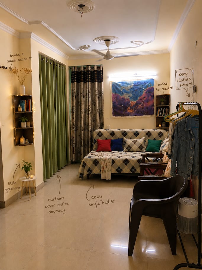 A single room with handwritten notes marking the bed, clothes rail, books, curtains and a small plant.